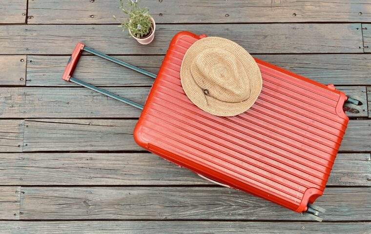 赤いスーツケースと麦わら帽子