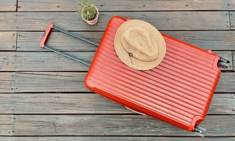 赤いスーツケースと麦わら帽子
